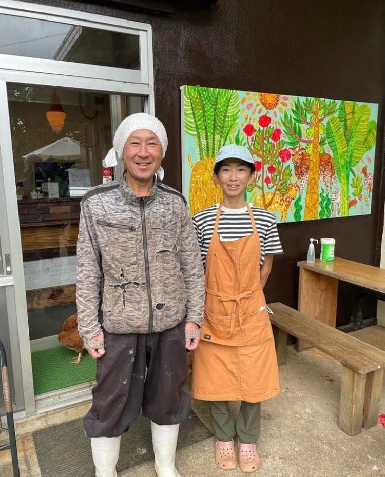 牧場の建物の前に立つ石川智樹と石川敦子。